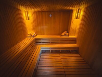 warmly lit sauna with two tier corner bench