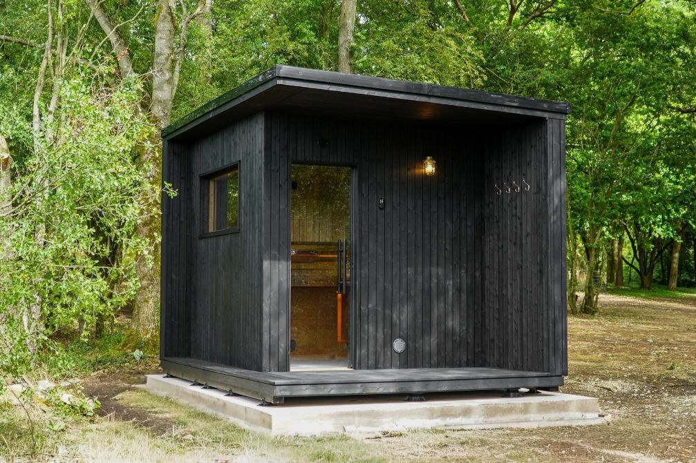 True North Eluna sauna model positioned in garden amongst trees on concrete pad